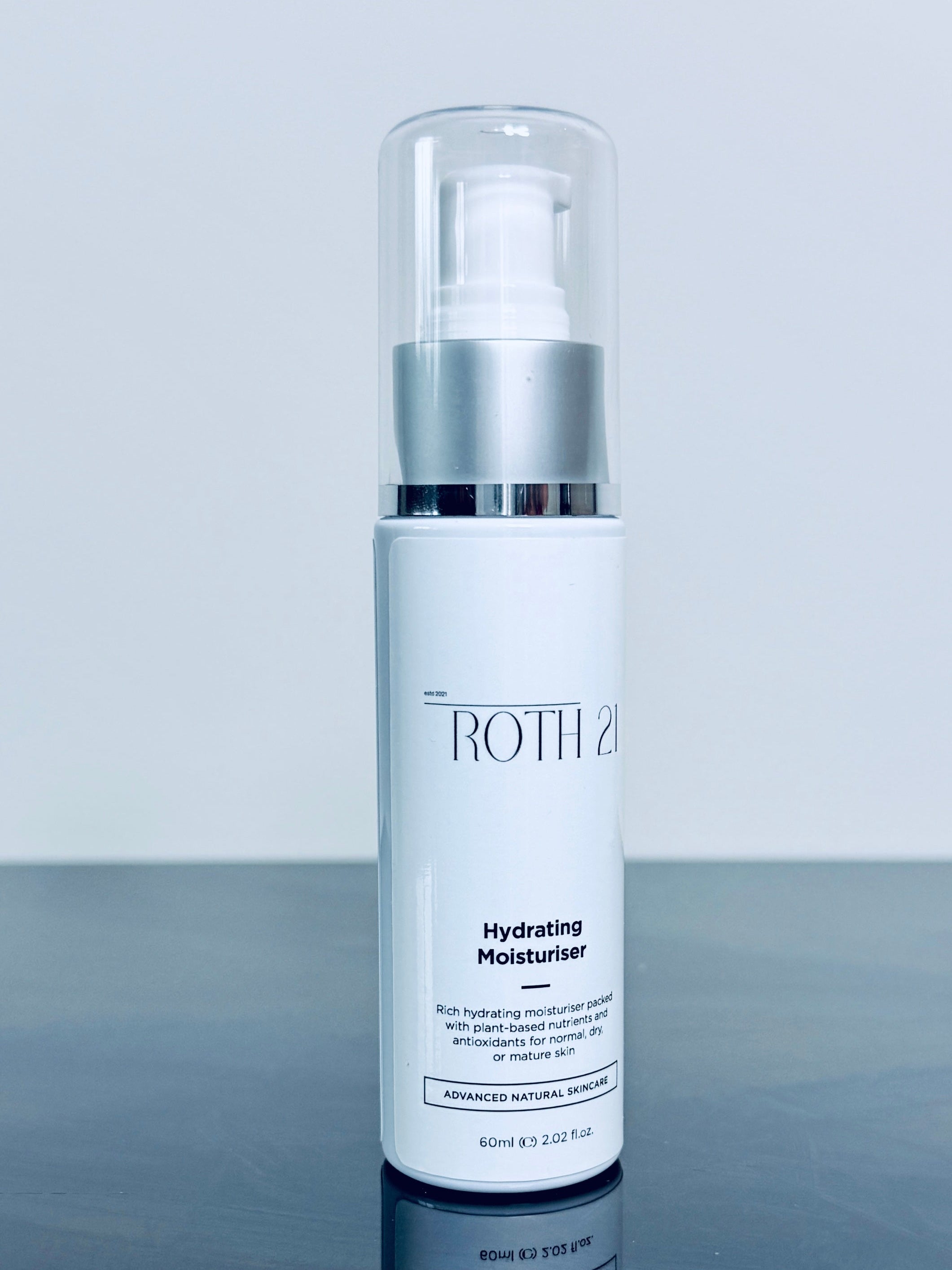 Skincare bottle with silver cap on a reflective surface and light gray background