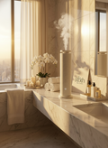 Modern bathroom with marble countertop, towels, and a diffuser with steam.
